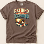 T-shirt with "Retired but not expired" text and a pill bottle.