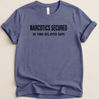 Blue t-shirt with "NARCOTICS SECURED IN TIME-DELAYED SAFE" text.