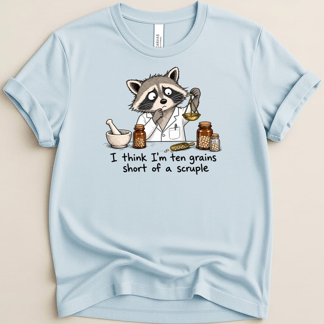 Light blue t-shirt with cartoon raccoon scientist using a scale and jars.