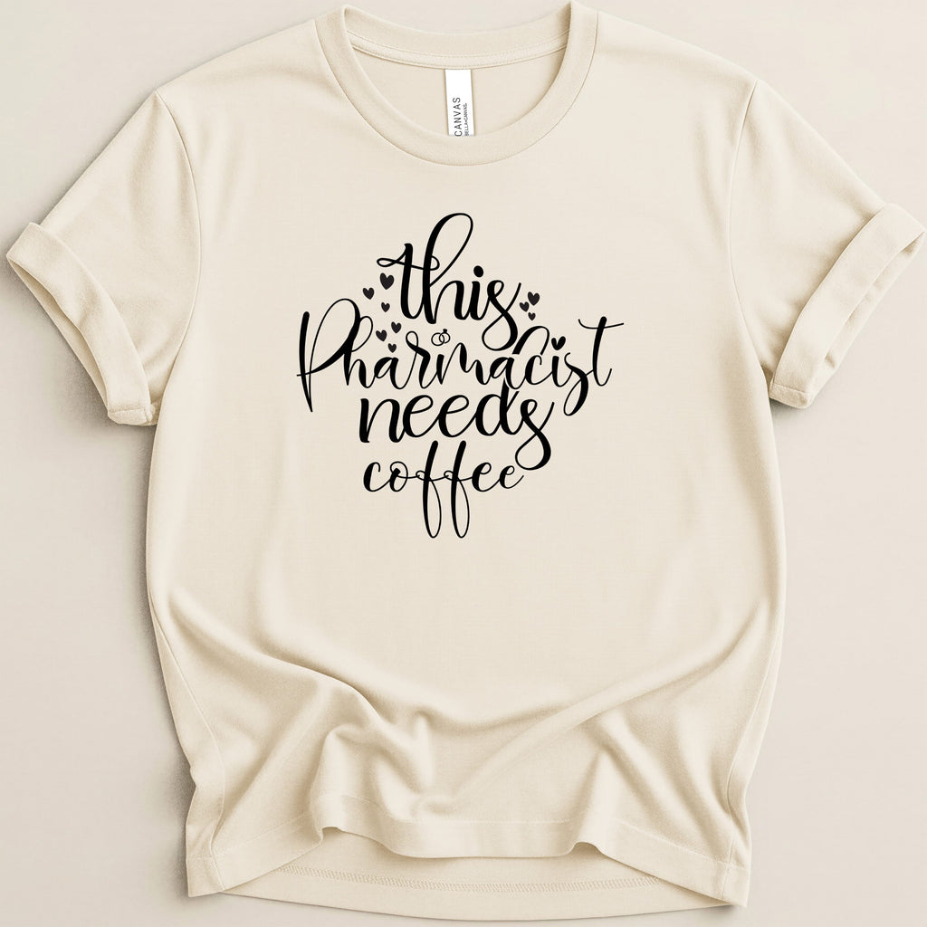 Cream t-shirt with "This pharmacist needs coffee" in black script.