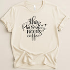 Cream t-shirt with "This pharmacist needs coffee" in black script.
