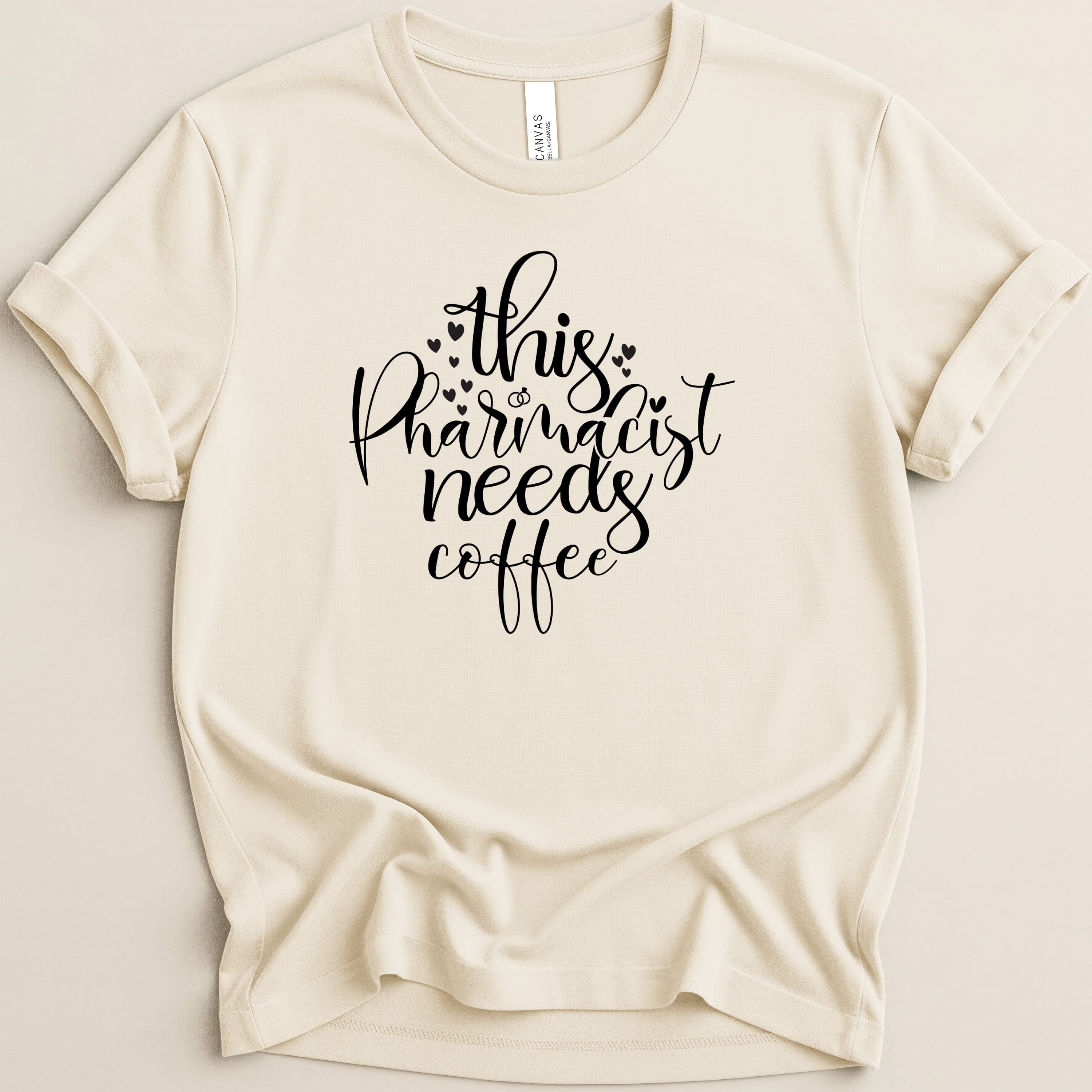 Cream t-shirt with "This pharmacist needs coffee" in black script.