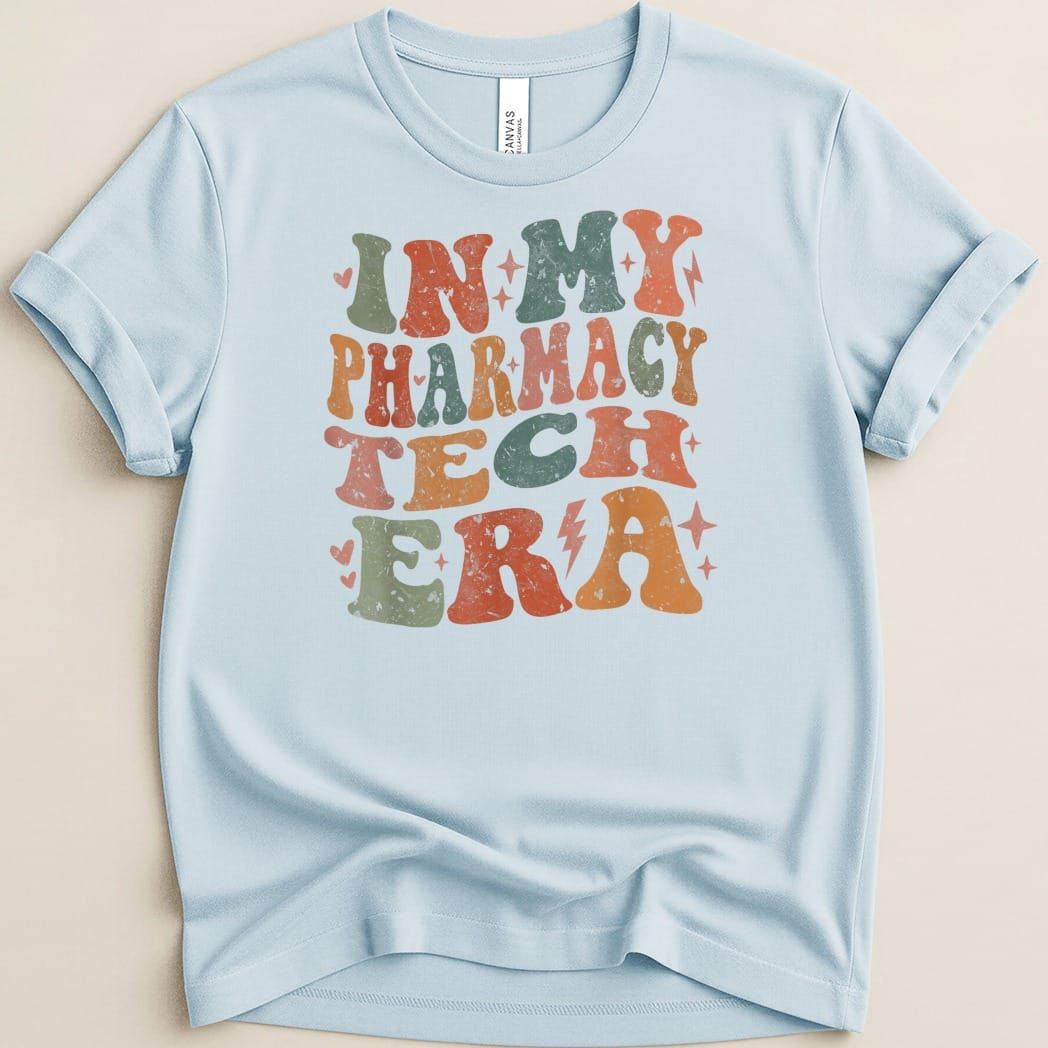 Light blue t-shirt with retro text "In My Pharmacy Tech Era" in colorful distressed font.