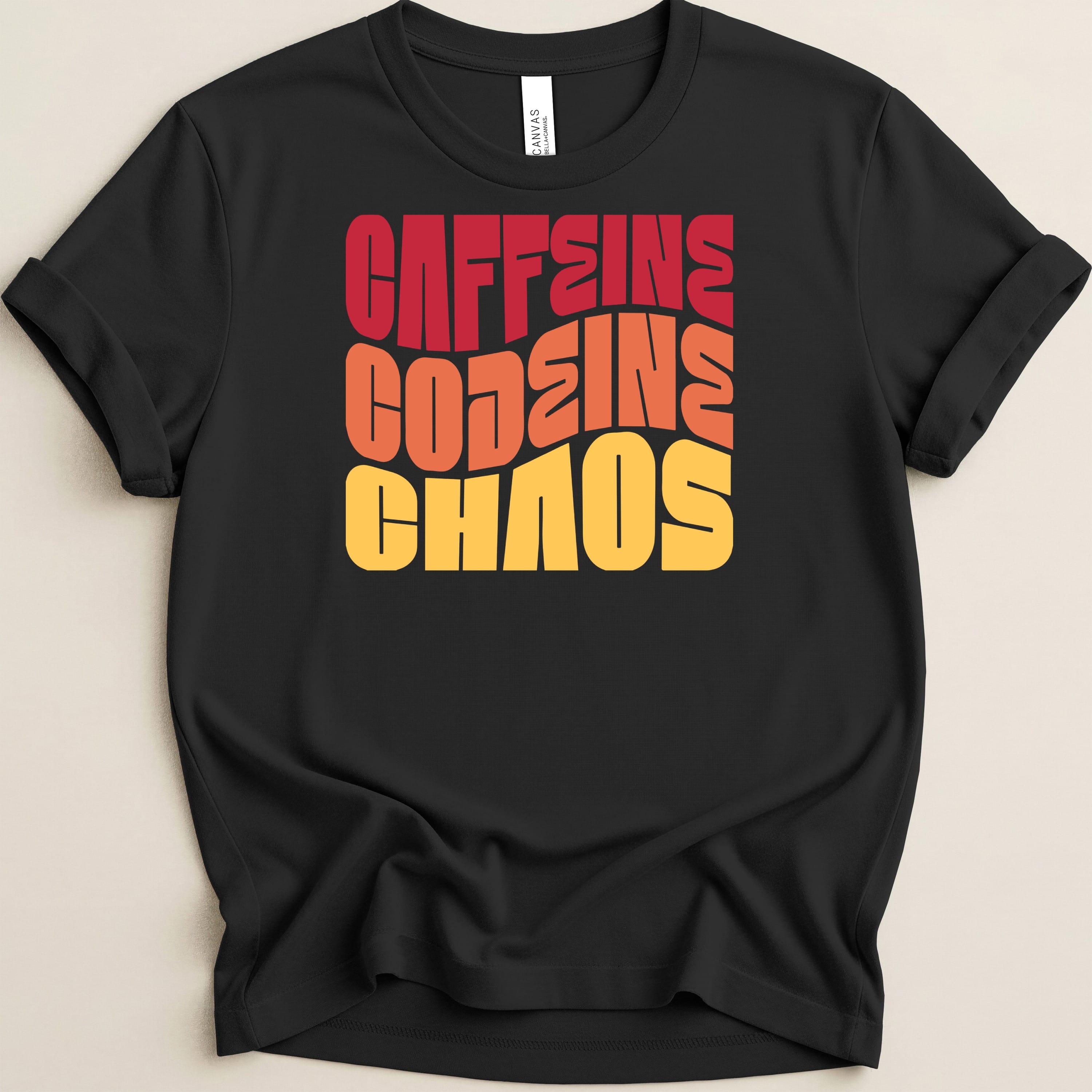 Black t-shirt with bold, wavy red, orange, and yellow text reading "CAFFEINE GODDESS CHAOS".