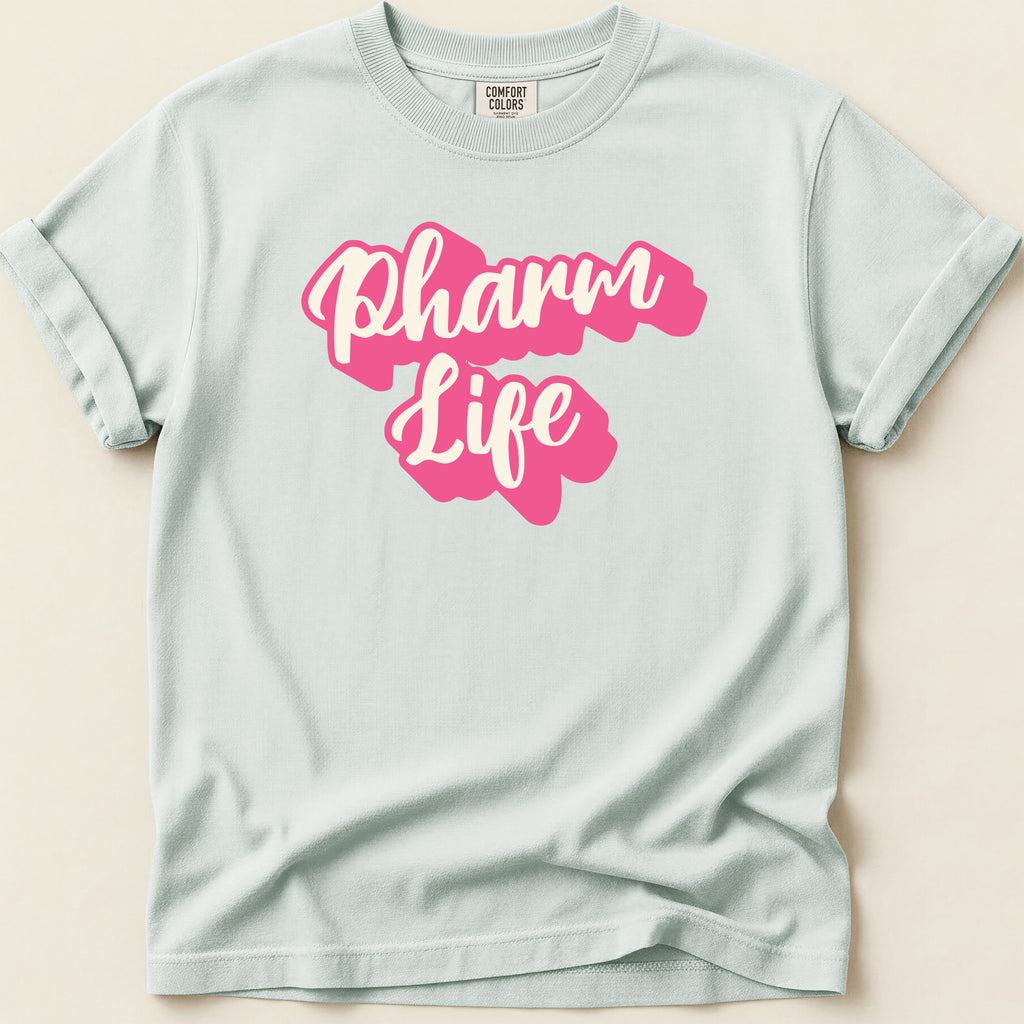 White Comfort Colors t-shirt with pink "Pharm Life" text.