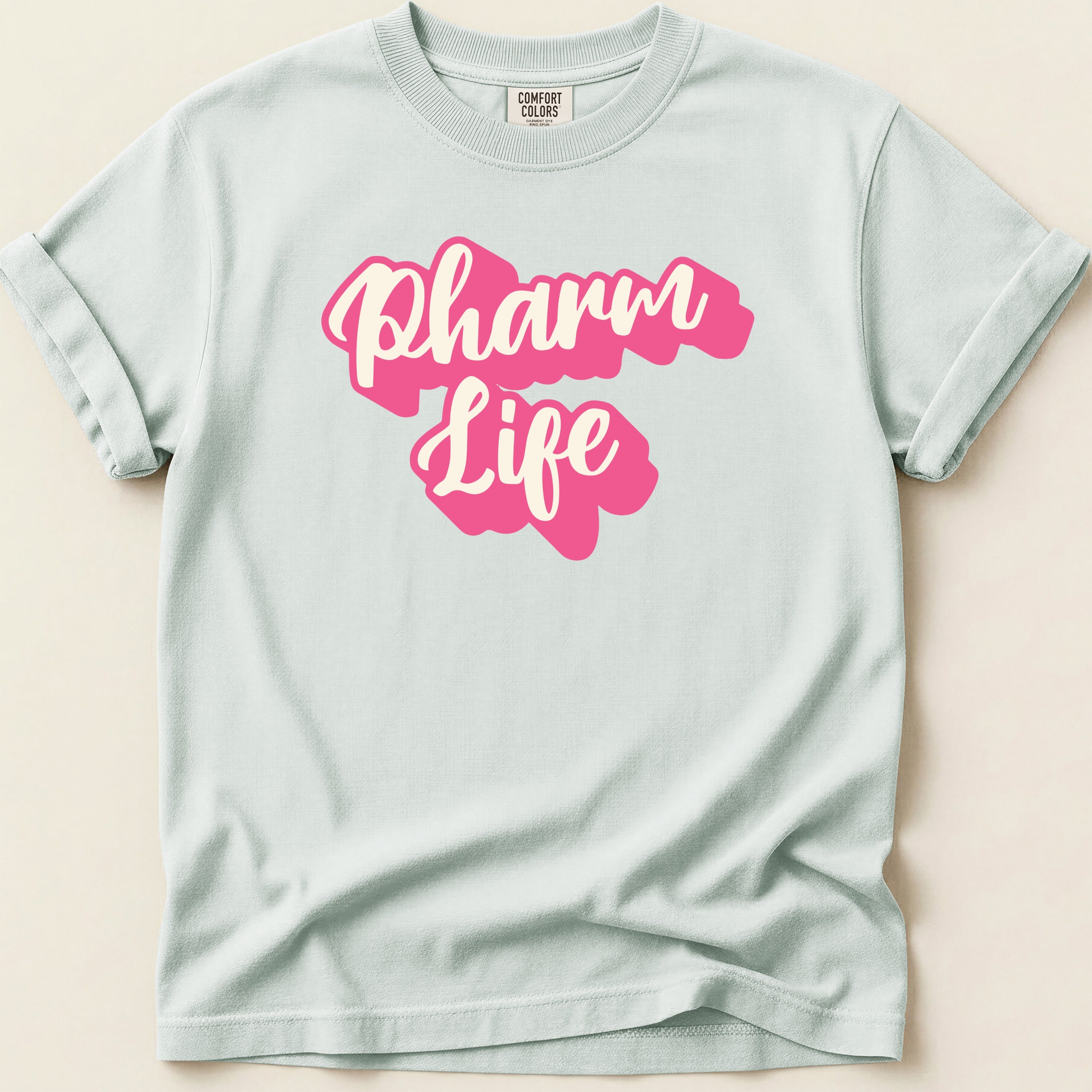 White Comfort Colors t-shirt with pink "Pharm Life" text.