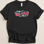 Black t-shirt with "DRUG DEALER" in wavy pink and blue text.