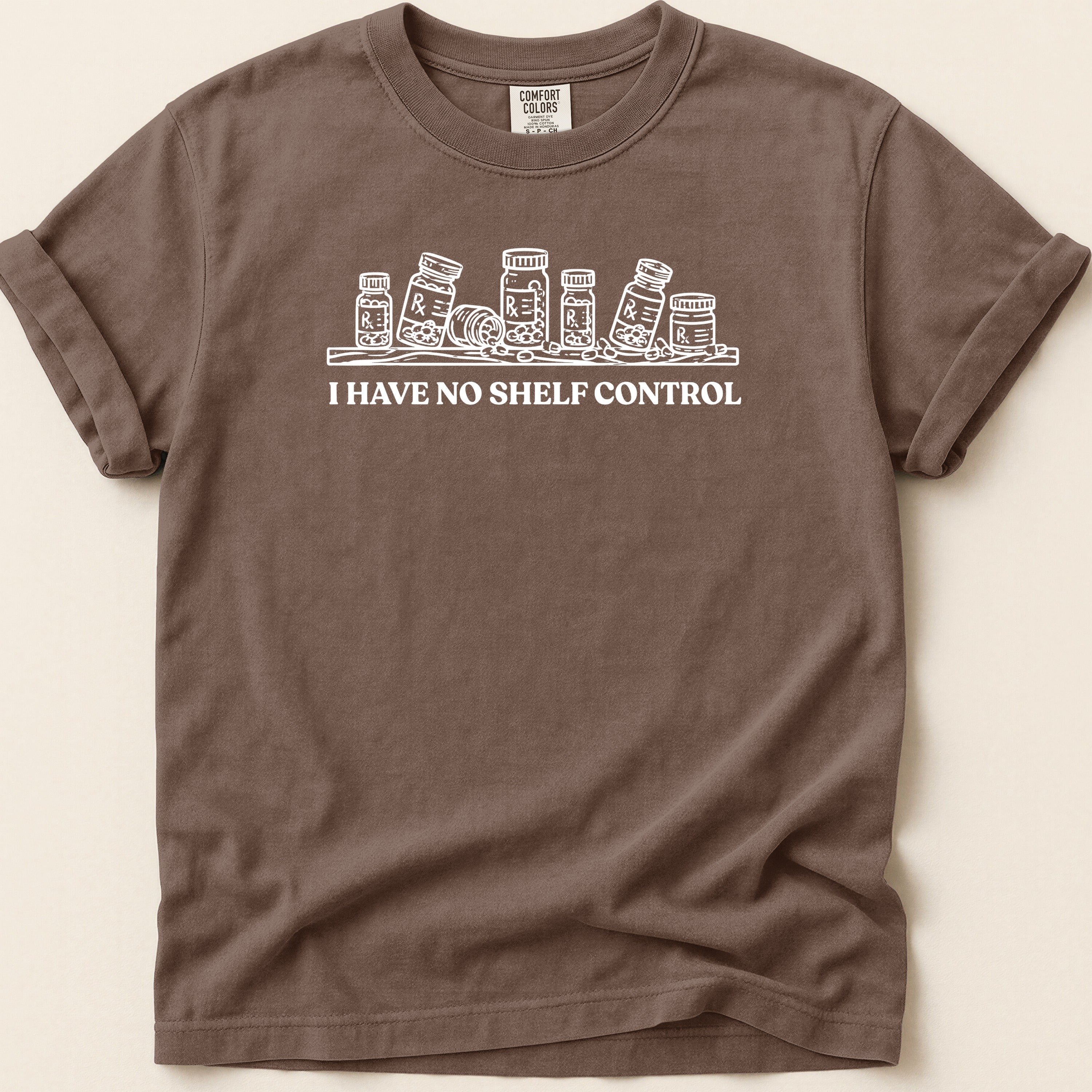 Brown t-shirt with white sketch of pill bottles and text "I HAVE NO SHELF CONTROL".