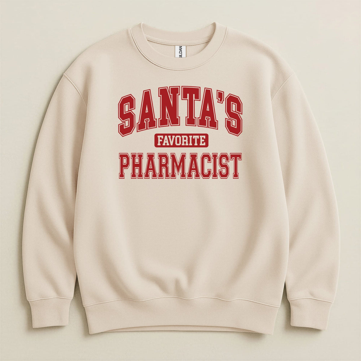 Beige crewneck sweatshirt with red collegiate lettering that reads SANTA'S FAVORITE PHARMACIST centered on the chest.