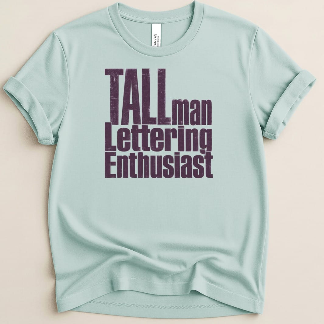 Light blue t-shirt with distressed purple text reading "TALLman Lettering Enthusiast".