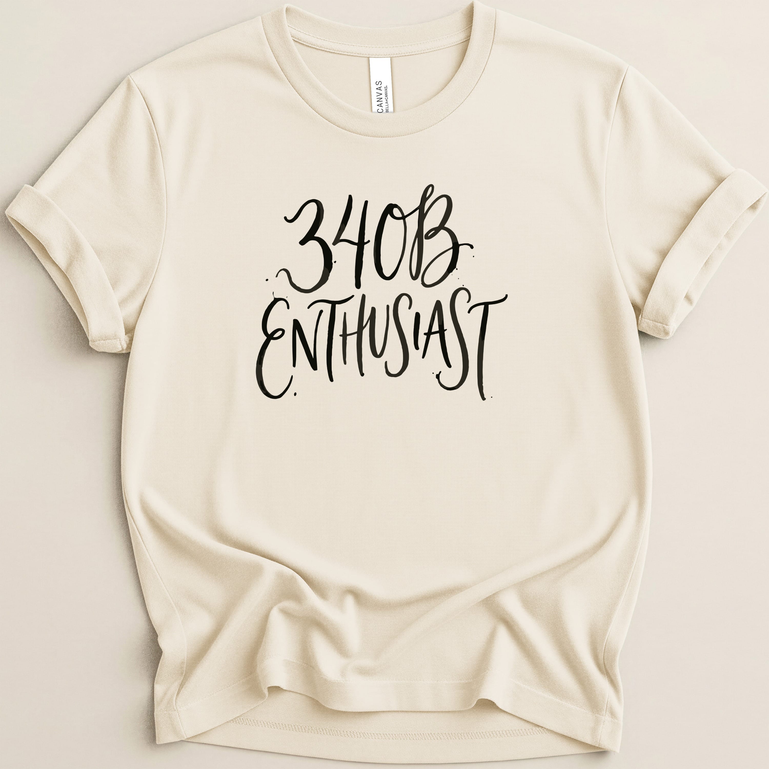 Cream t-shirt with "34B Enthusiast" in black script text.