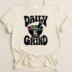 Cream t-shirt with black "DAILY" and "GRIND" text and a mortar and pestle with pills.