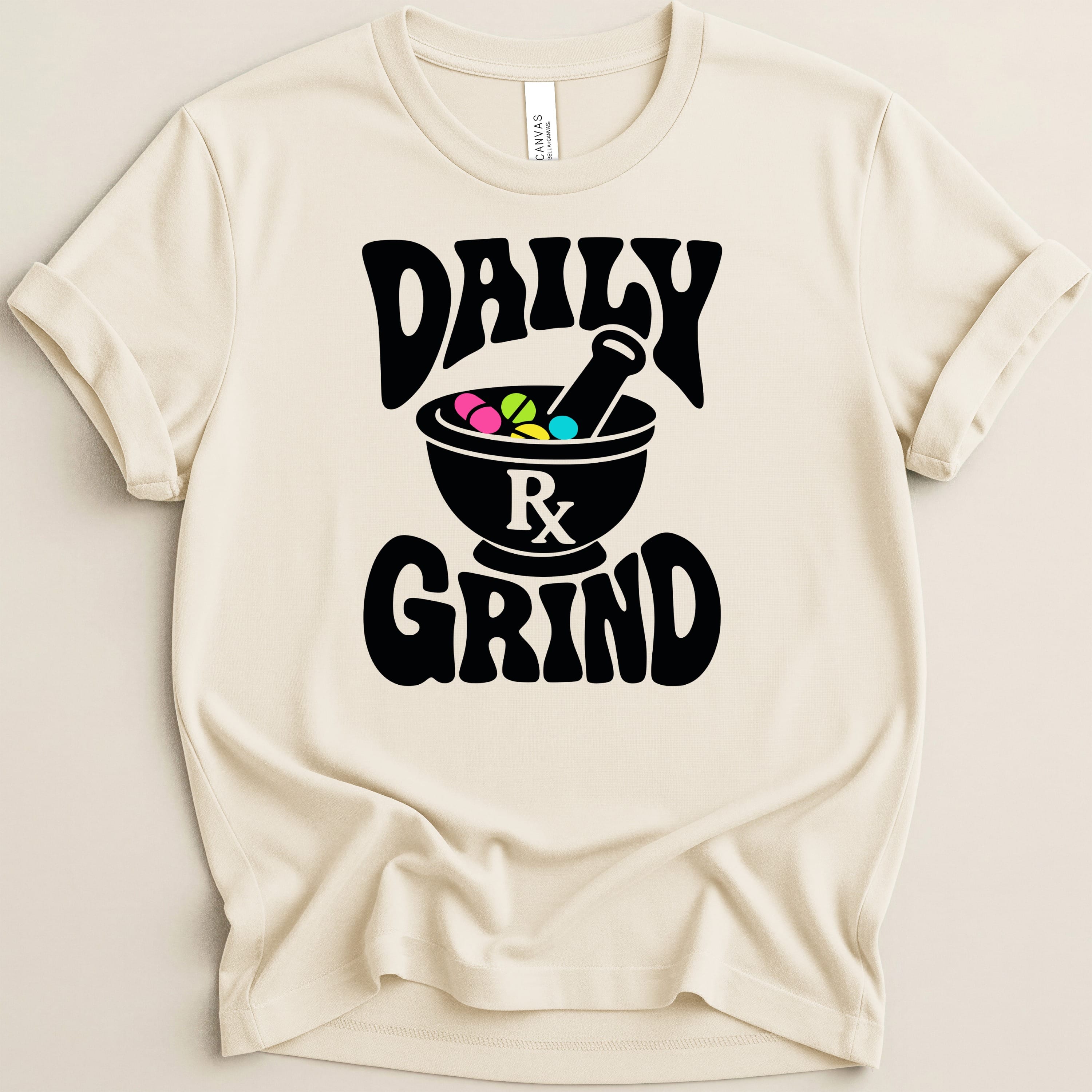 Cream t-shirt with black "DAILY" and "GRIND" text and a mortar and pestle with pills.