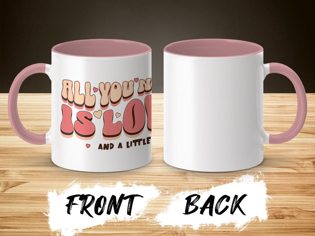 Two white mugs with pink handles and interiors; front shows "All you're gonna need is love and a little coffee."