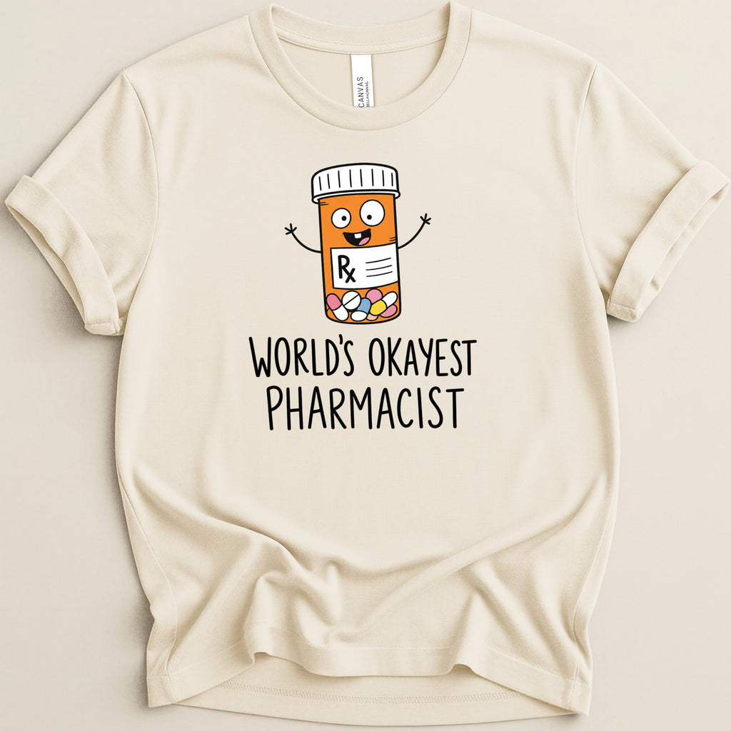 Cream t-shirt with cartoon pill bottle and "World's Okayest Pharmacist" text.