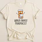 Cream t-shirt with cartoon pill bottle and "World's Okayest Pharmacist" text.