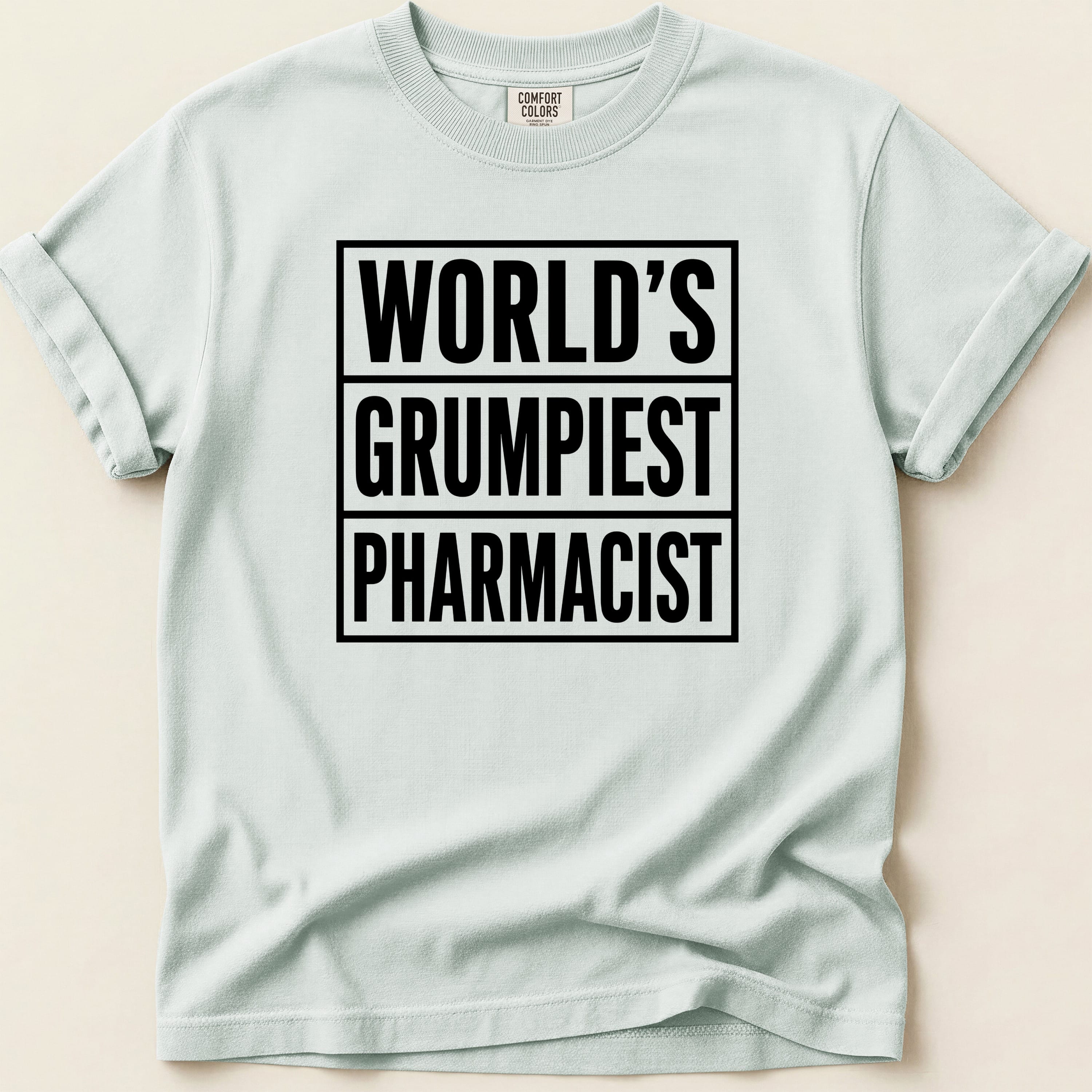 Light blue t-shirt with black text "WORLD'S GRUMPIEST PHARMACIST".