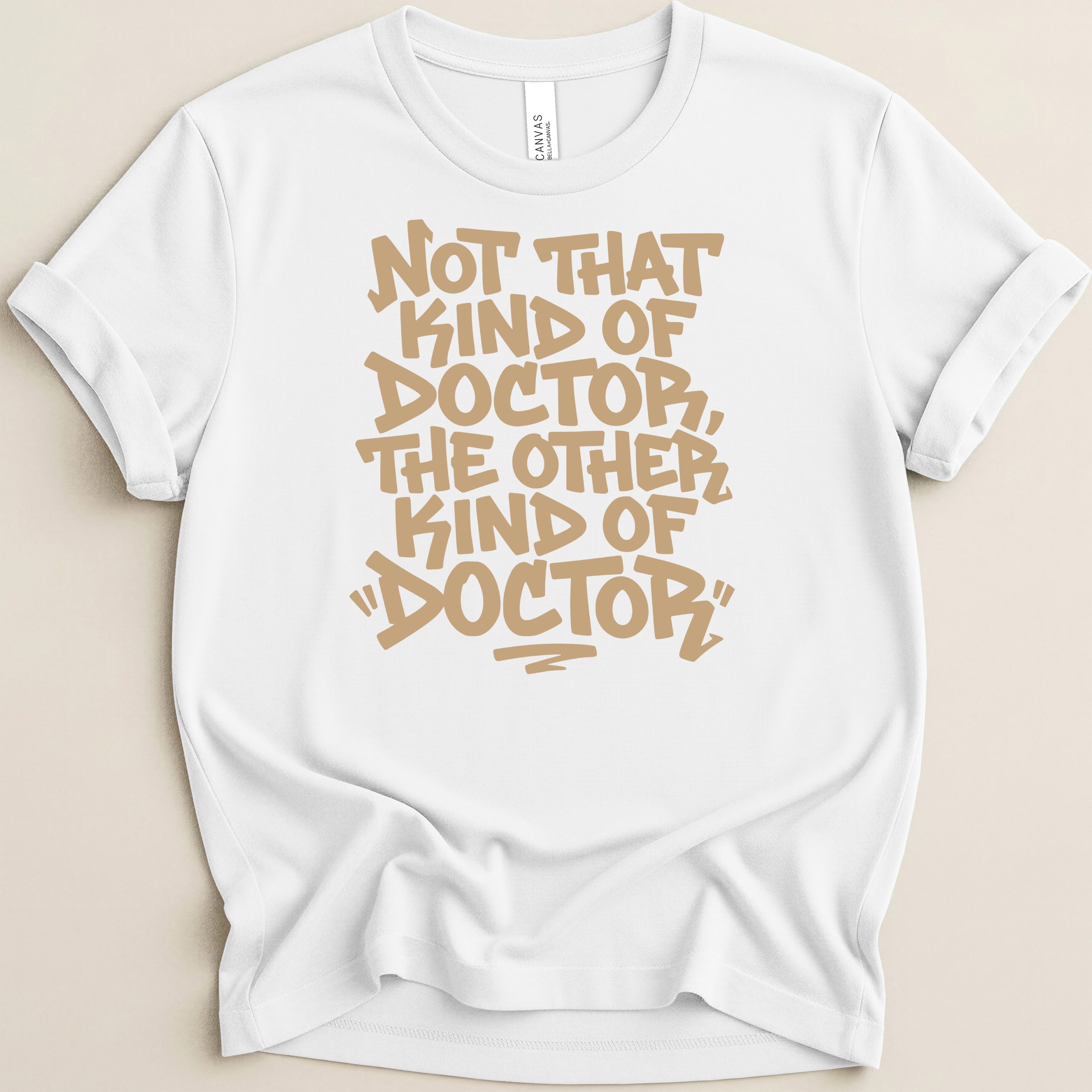 White t-shirt with tan text reading "Not that kind of doctor, the other kind of doctor".