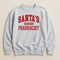 A light gray crewneck sweatshirt featuring red collegiate-style text that reads SANTA'S FAVORITE PHARMACIST.