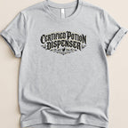 Grey t-shirt with "Certified Potion Dispenser" text in ornate black lettering.
