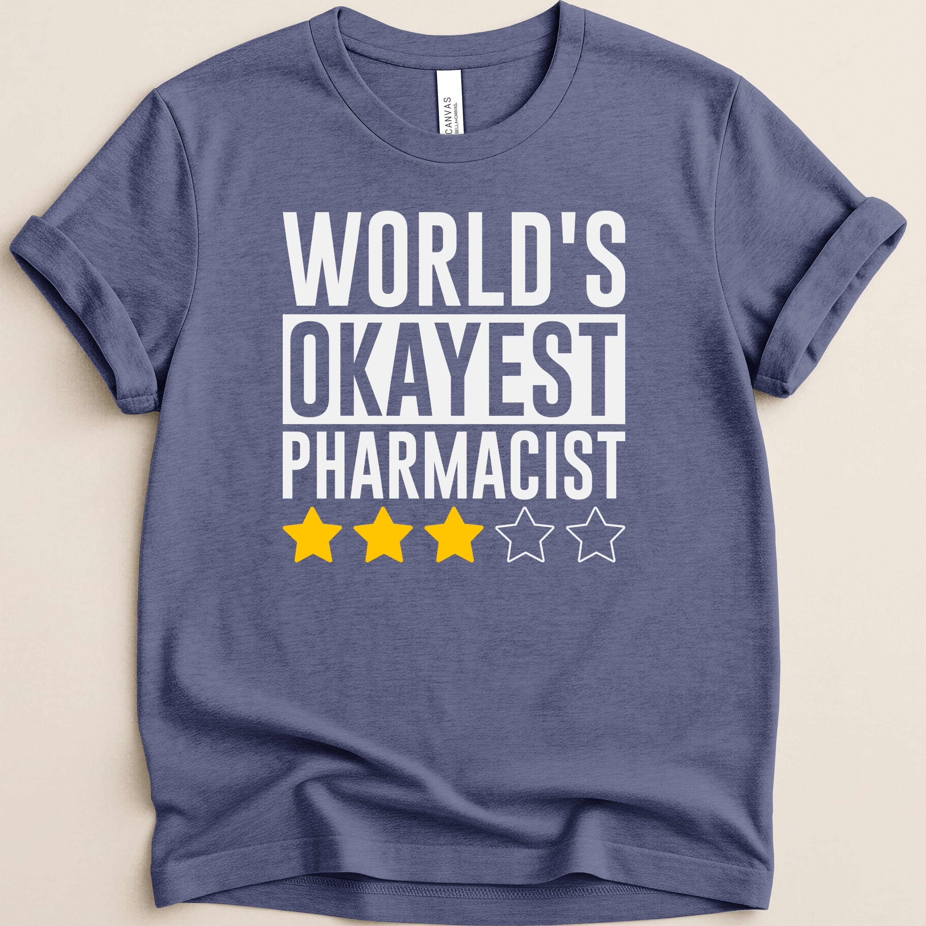 Navy t-shirt with white text reading "WORLD'S OKAYEST PHARMACIST" and three yellow stars.