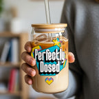 Glass tumbler with "Perfectly Dosed" graphic and straw held by a person.