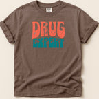 Brown t-shirt with "DRUG EXPERT" in distressed orange and teal lettering.