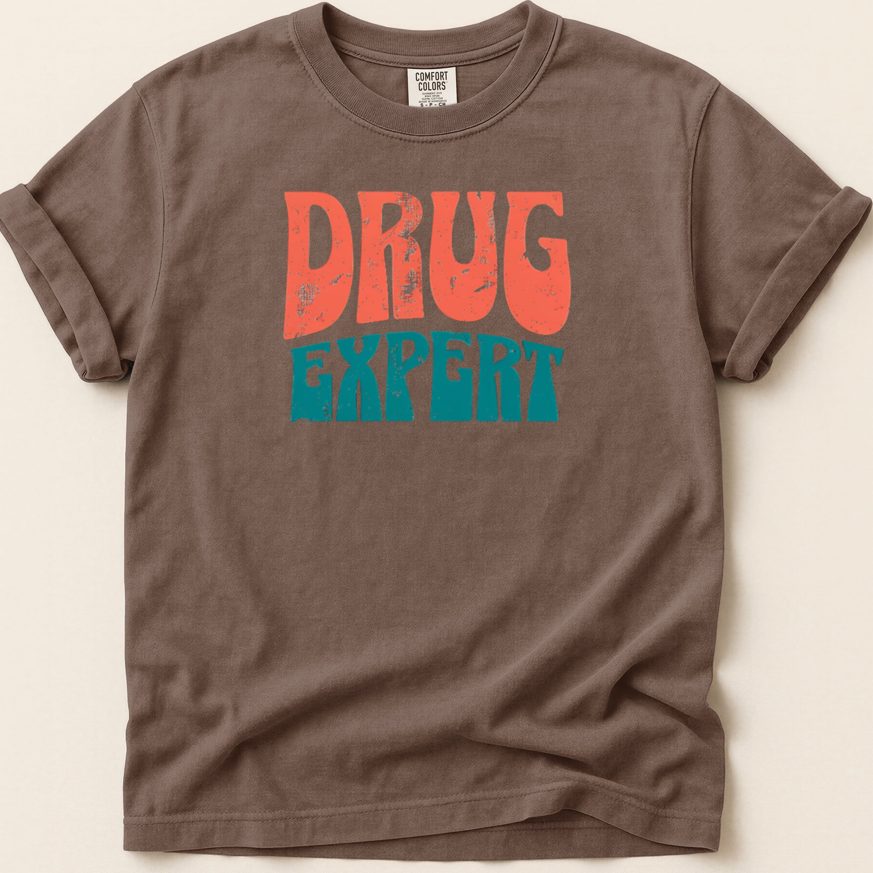 Brown t-shirt with "DRUG EXPERT" in distressed orange and teal lettering.