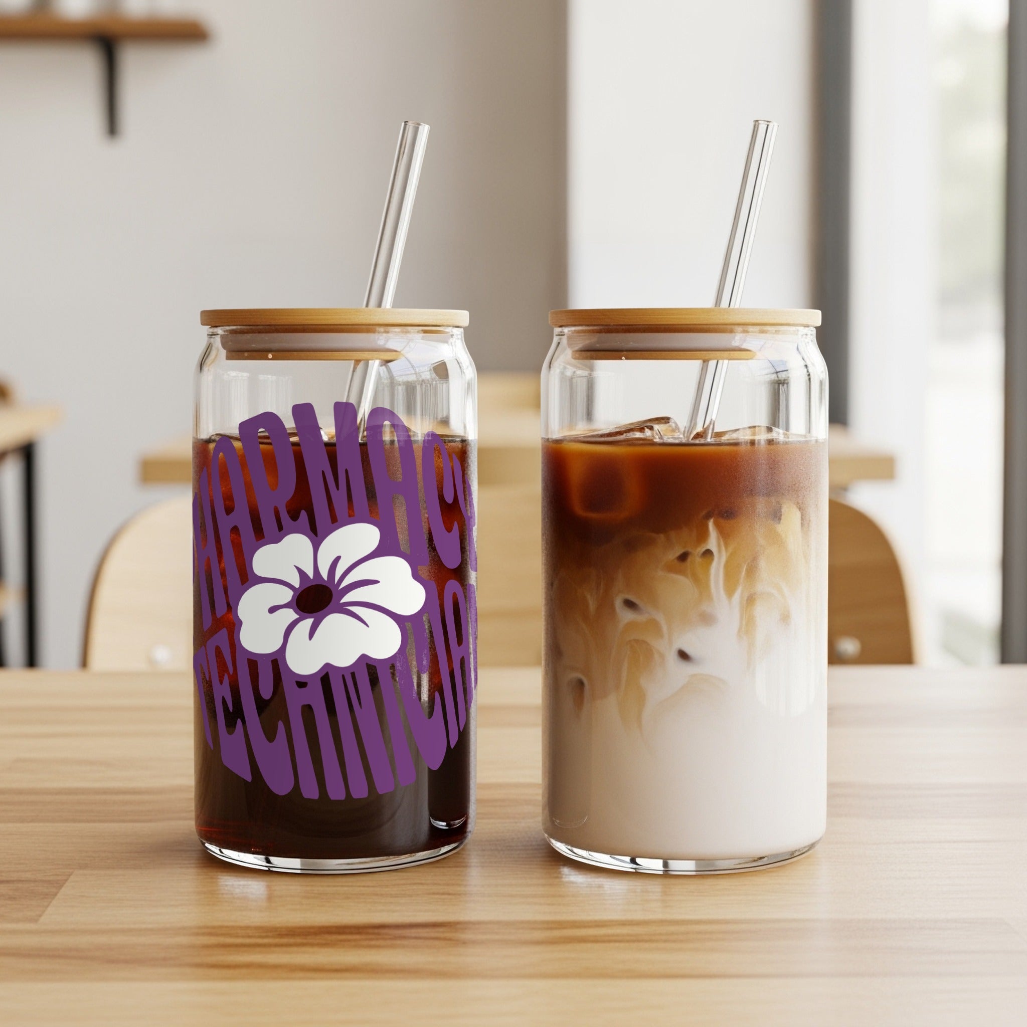 Two glass tumblers with straws, one with purple text and flower, one with iced coffee.