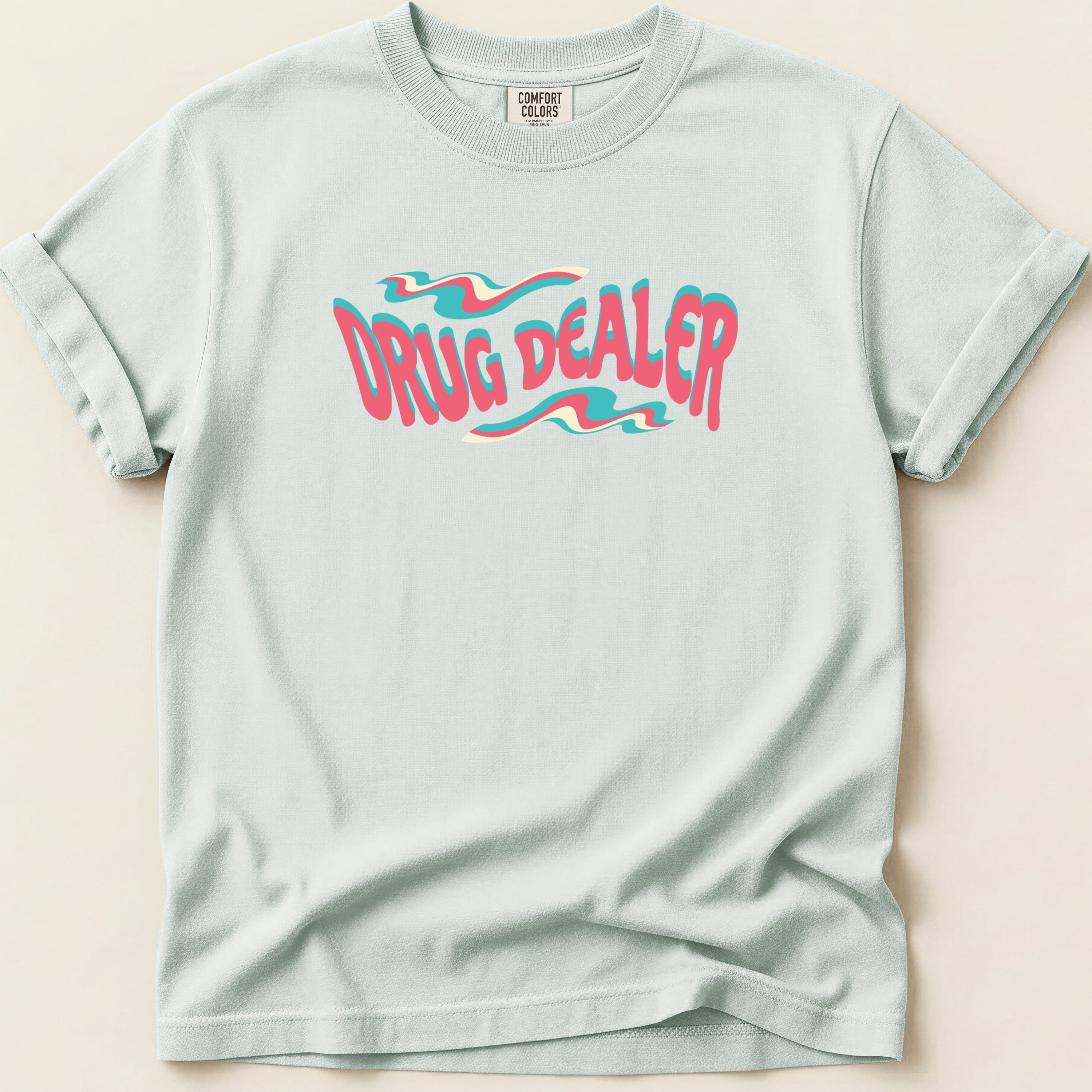 Light blue t-shirt with "DRUG DEALER" text in wavy pink and teal lettering.