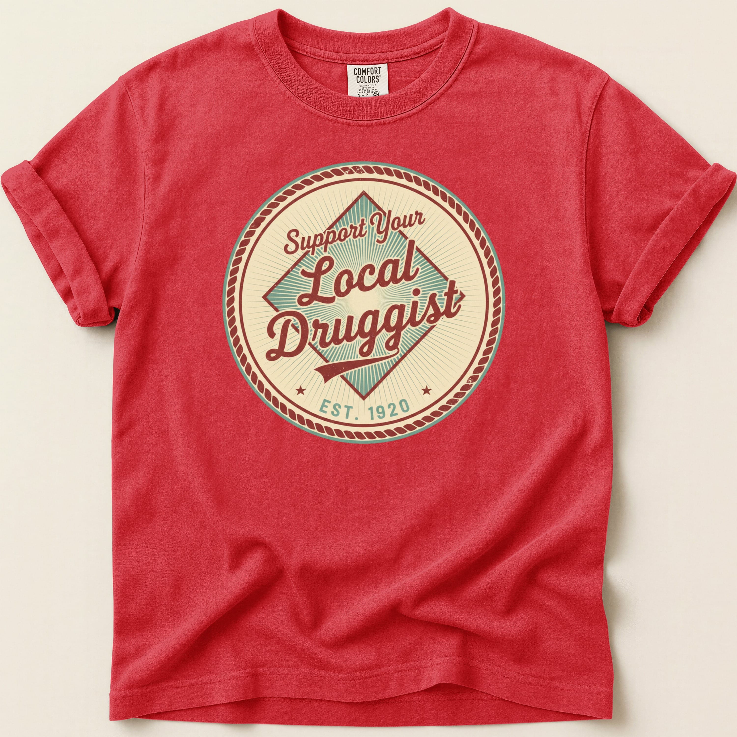 Red t-shirt with circular "Support Your Local Druggist EST. 1920" graphic.