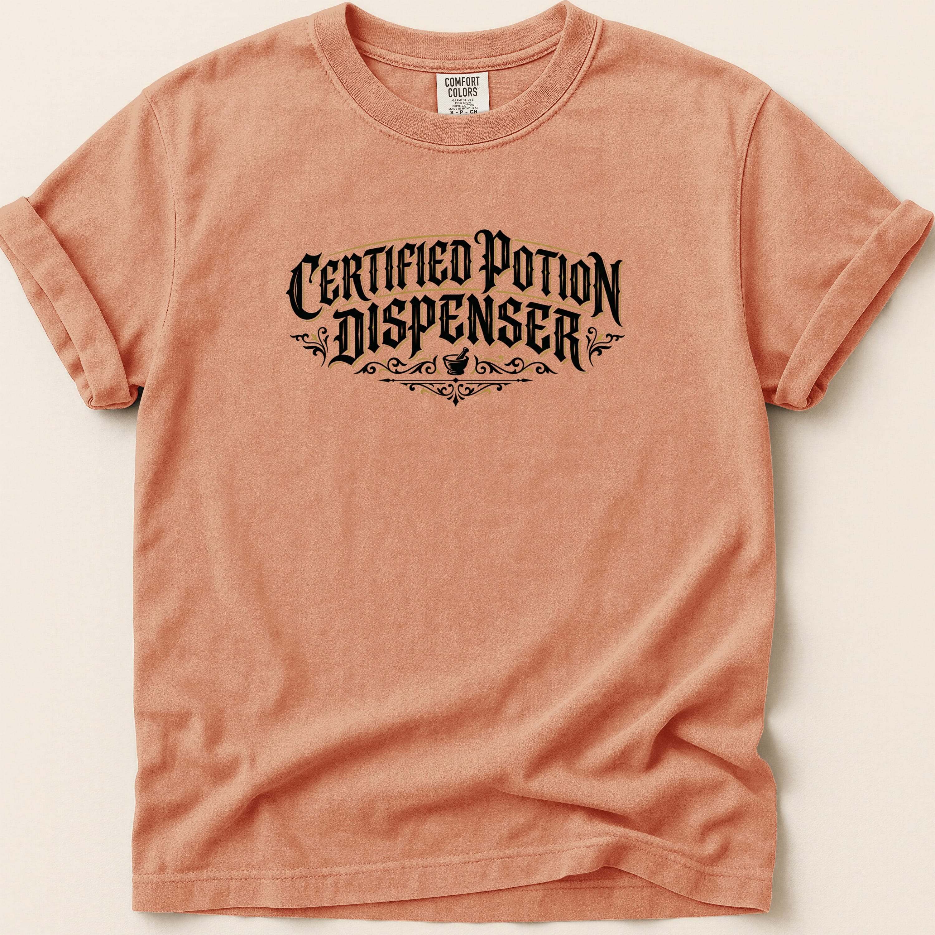 Peach t-shirt with black "Certified Potion Dispenser" text and decorative elements.