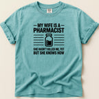 T-shirt with "My wife is a pharmacist. She hasn't killed me, yet but she knows how" text.