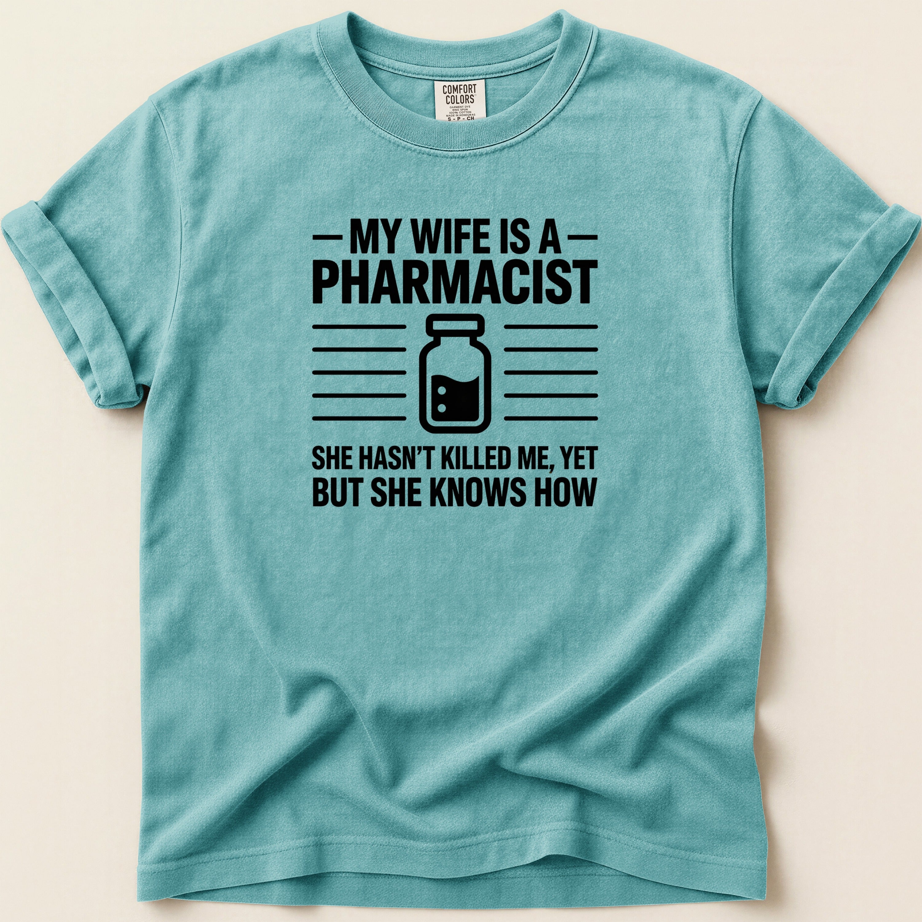 T-shirt with "My wife is a pharmacist. She hasn't killed me, yet but she knows how" text.