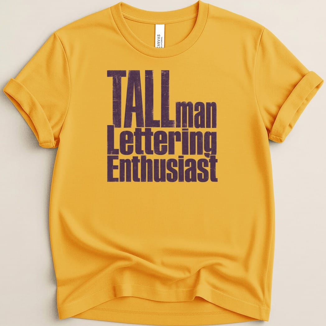 Yellow t-shirt with dark purple distressed text "TALLman Lettering Enthusiast".