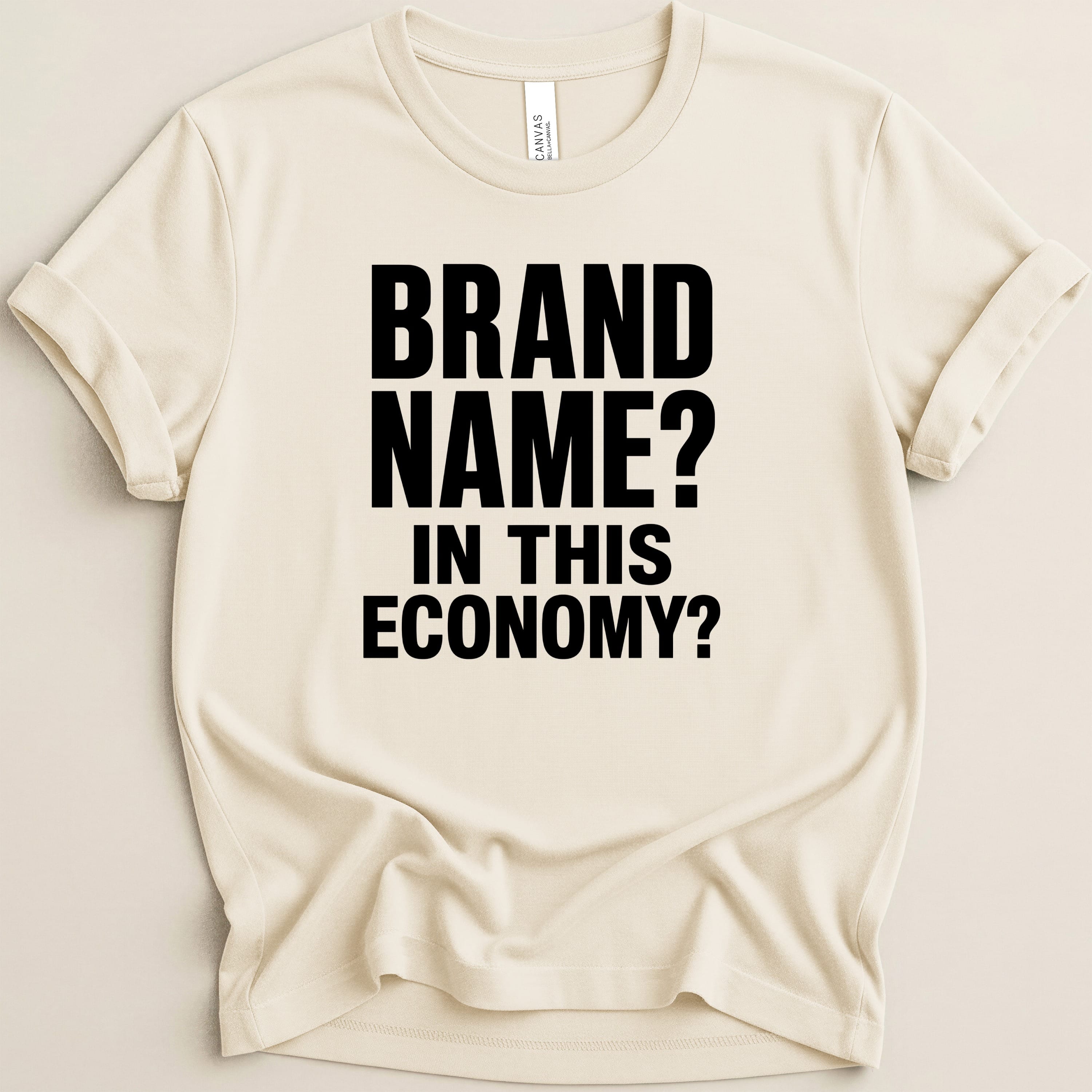 Cream t-shirt with black text that reads "BRAND NAME? IN THIS ECONOMY?".