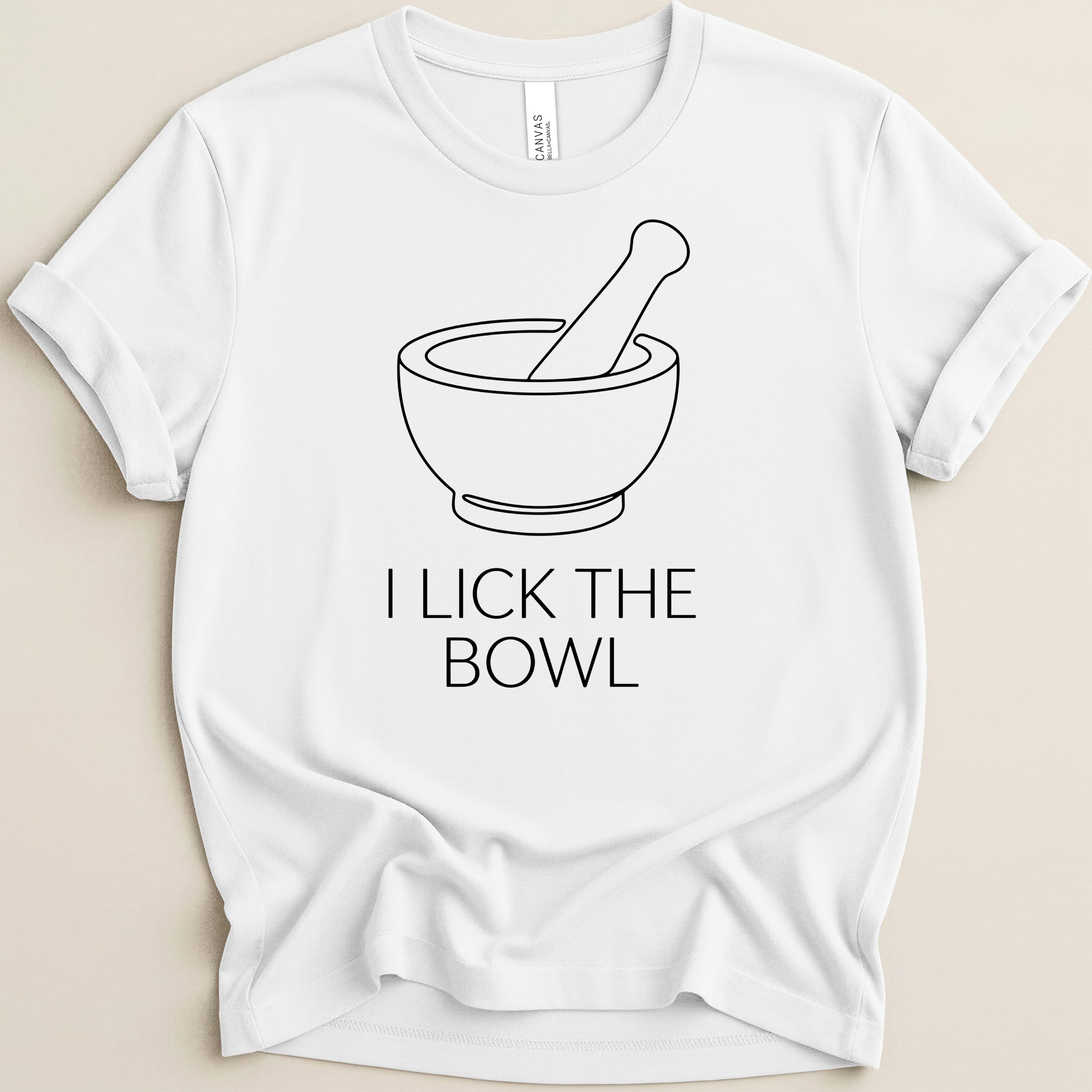 White t-shirt with black line drawing of a mortar and pestle and text "I LICK THE BOWL".