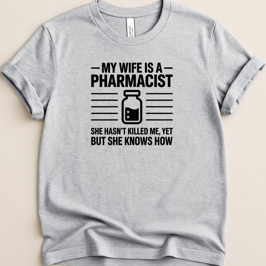 Gray t-shirt with text: "MY WIFE IS A PHARMACIST SHE HASN'T KILLED ME, YET BUT SHE KNOWS HOW".