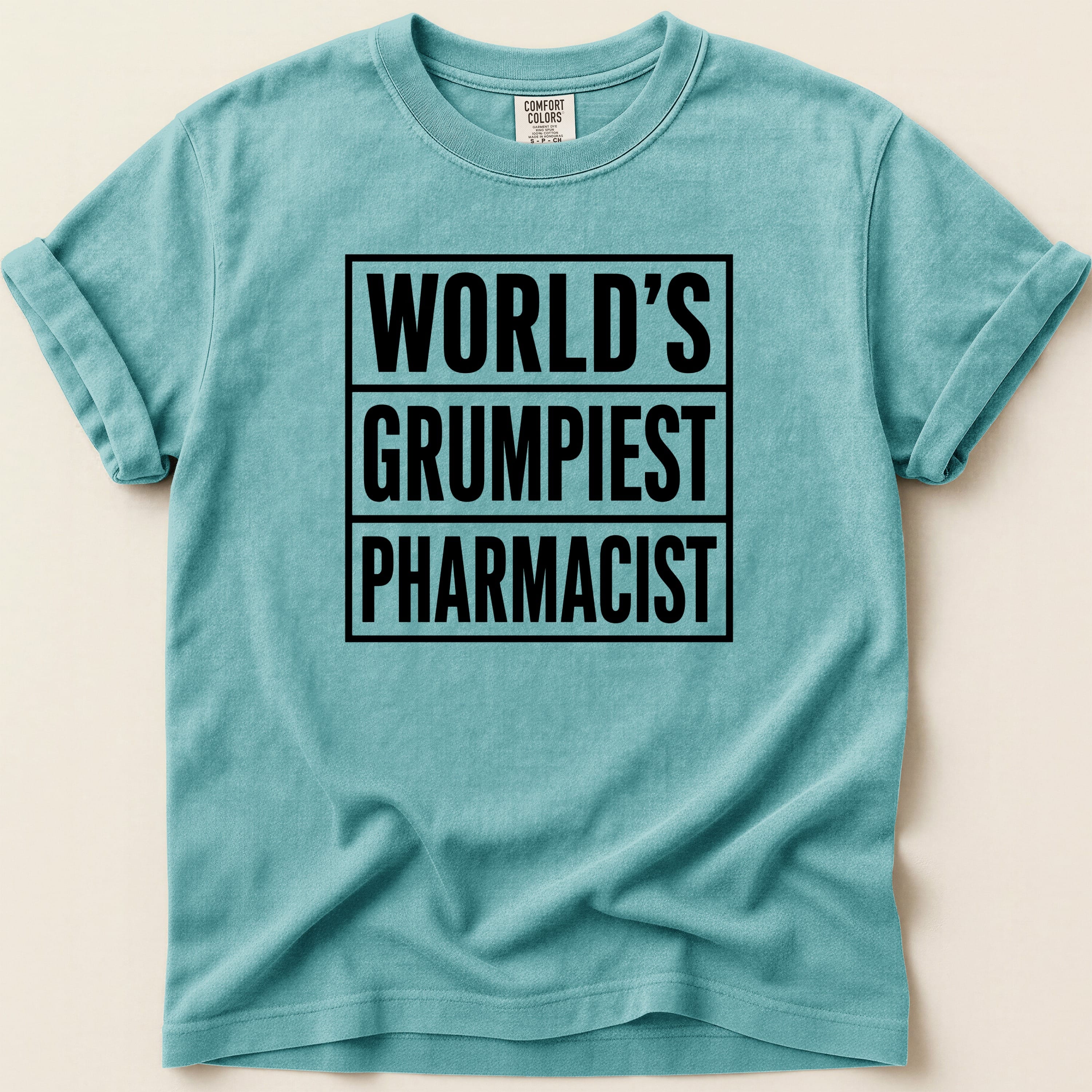 Teal t-shirt with black text "WORLD'S GRUMPIEST PHARMACIST".