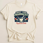 Cream t-shirt with "TRUST YOUR PHARMACIST Dose of Care, Daily" text and medical icons.