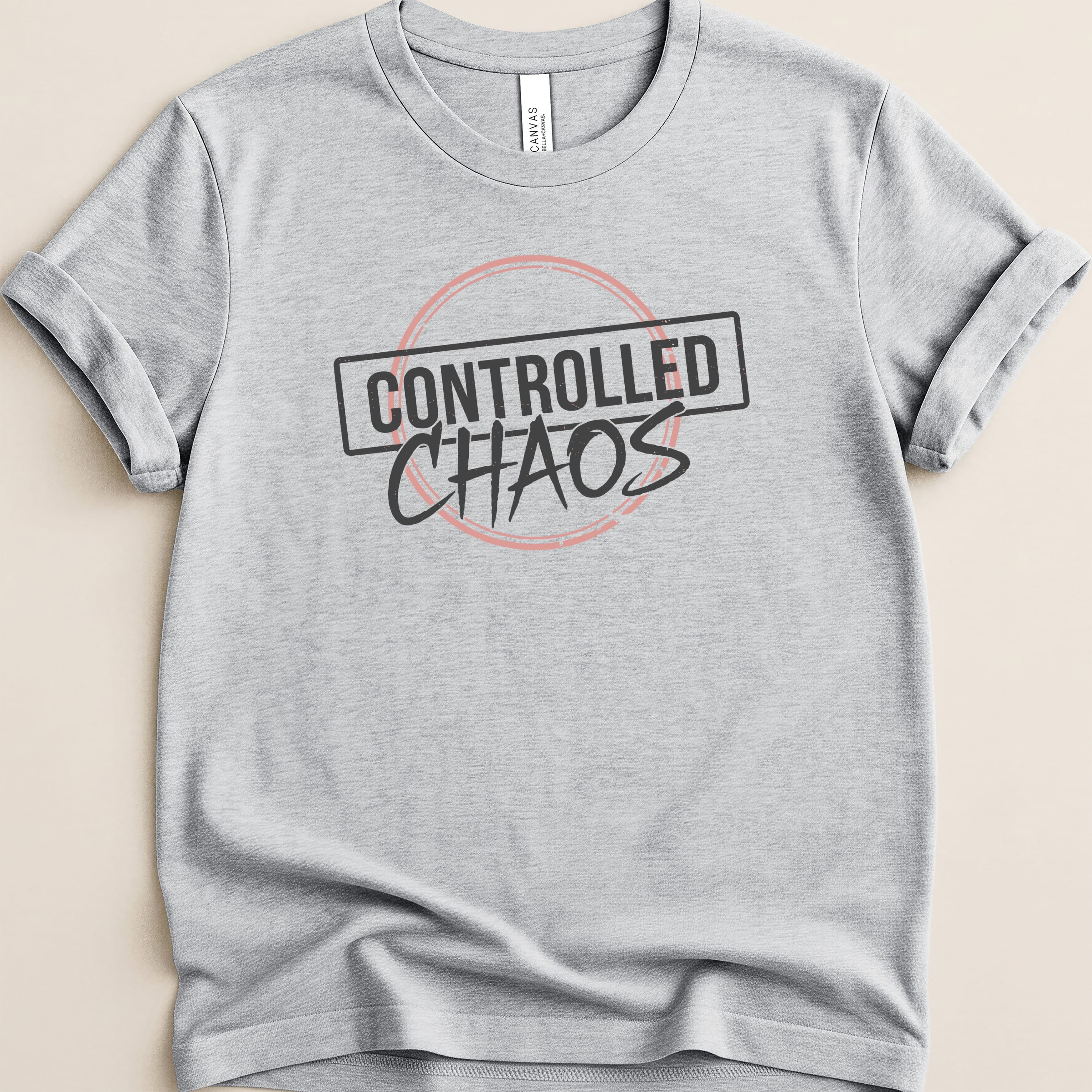 Grey t-shirt with "CONTROLLED CHAOS" text in a black box with a pink outline.