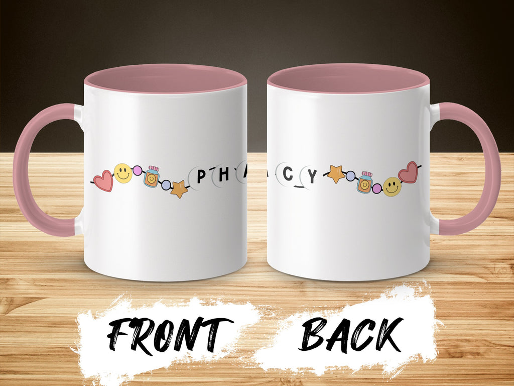 White mug with pink handle, featuring smiley faces and pharmacy-themed icons.