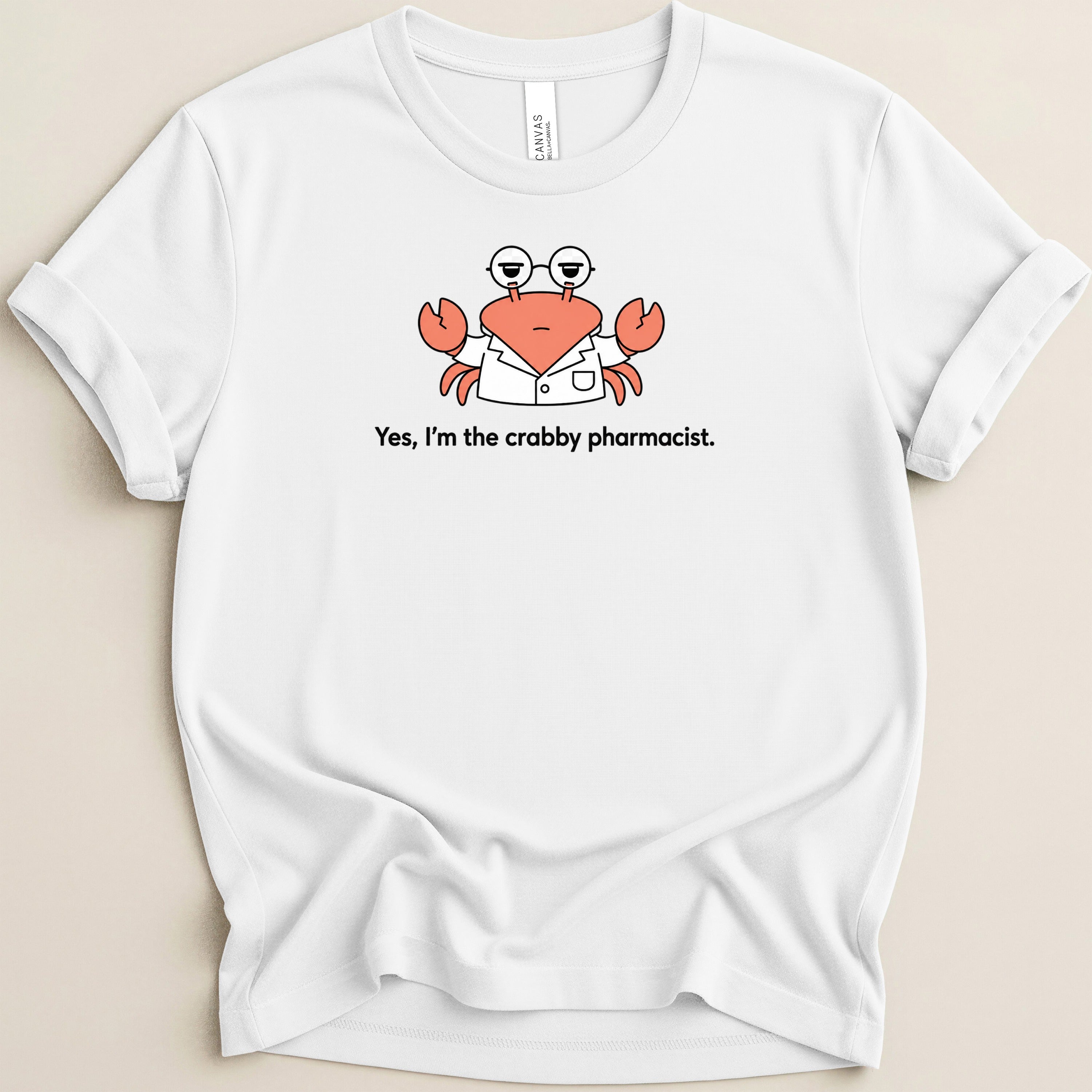 White t-shirt with a cartoon crab wearing glasses and a lab coat that says "Yes, I'm the crabby pharmacist."
