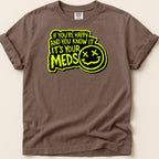 Brown t-shirt with neon yellow text "IF YOU'RE HAPPY AND YOU KNOW IT IT'S YOUR MEDS" and a smiley face.