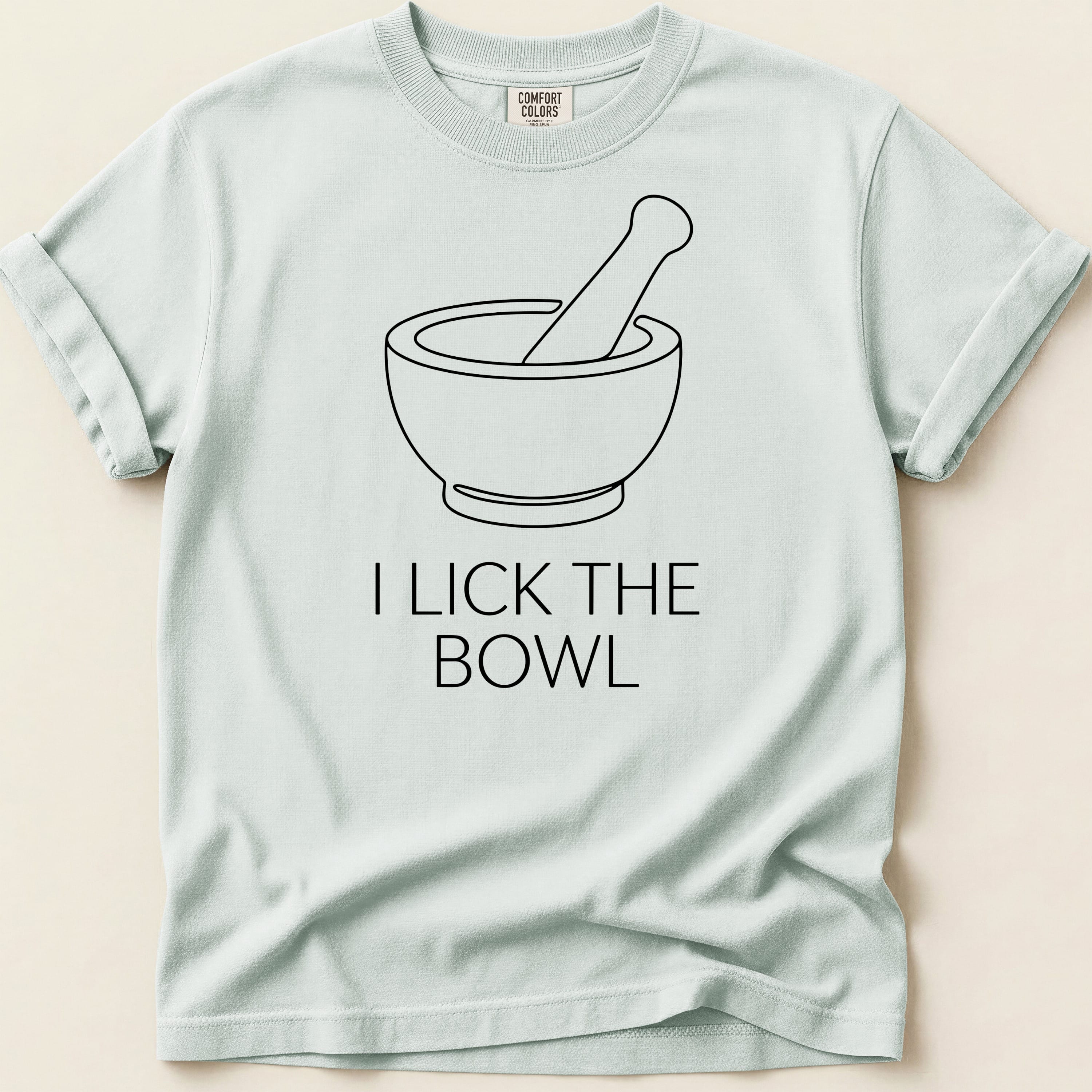 Light blue t-shirt with black line art of a mortar and pestle and text "I LICK THE BOWL".