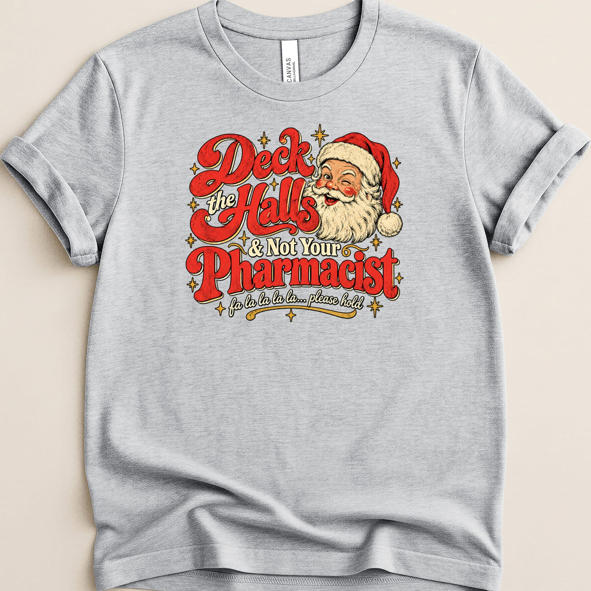 A heather grey t-shirt featuring a retro graphic of Santa Claus and the text Deck the Halls & Not Your Pharmacist.