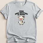 Grey t-shirt with cartoon cow holding a pill bottle, text reads "Your Moo-dication is Ready".