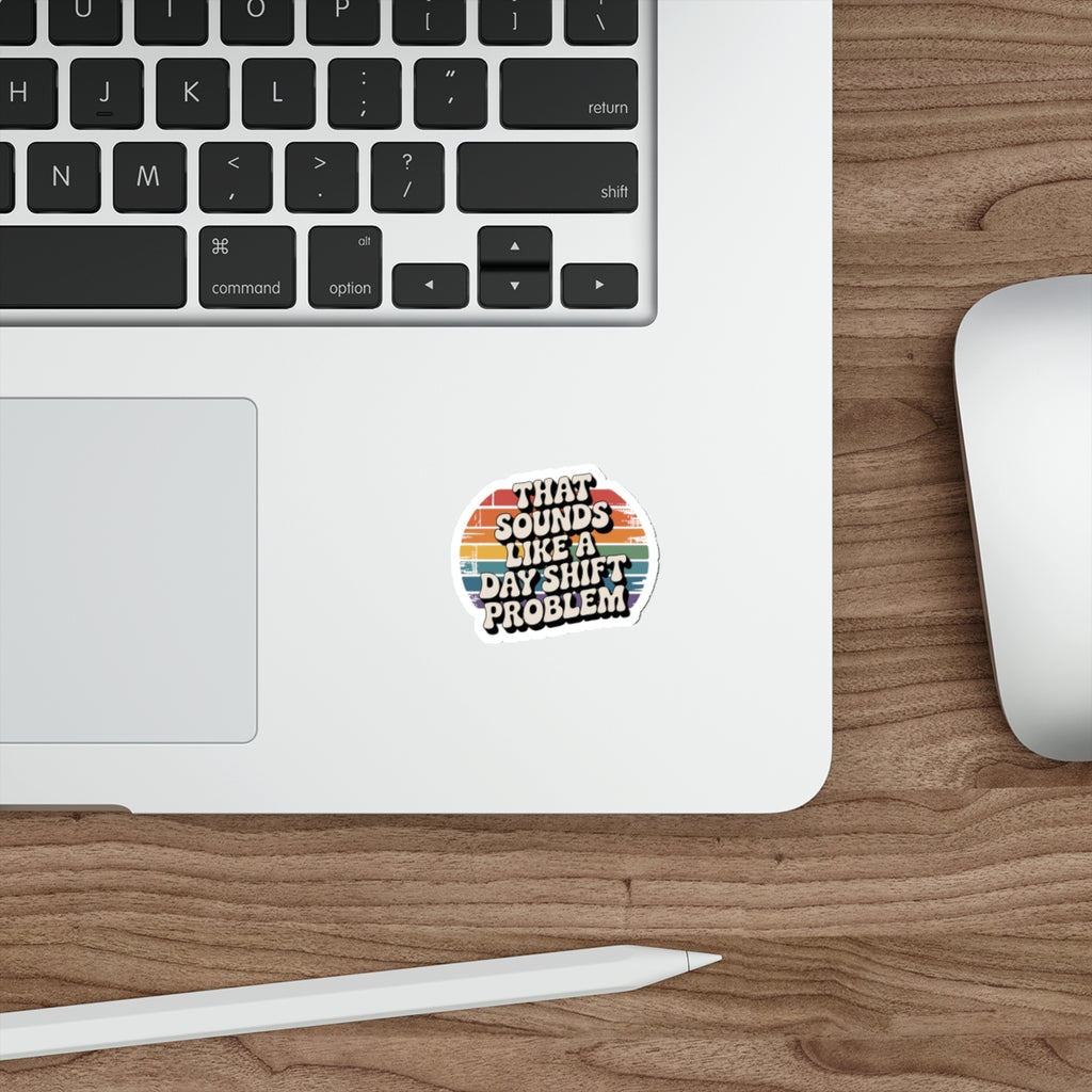 Sticker with text "THAT SOUNDS LIKE A DAY SHIFT PROBLEM" on a laptop.