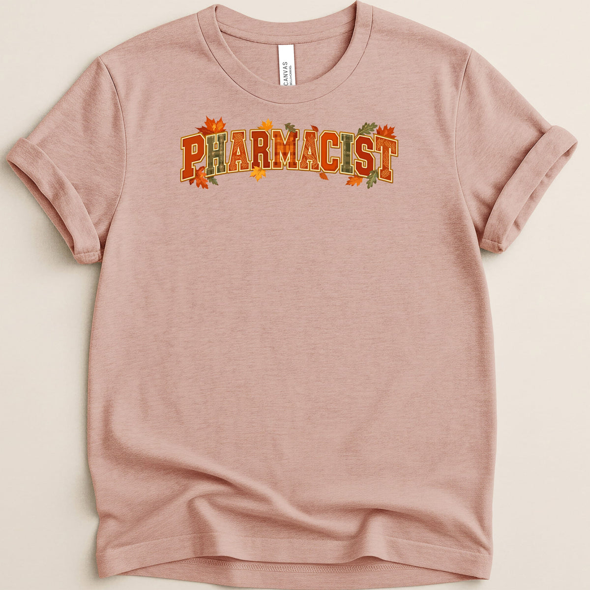 Mauve short-sleeve t-shirt with rolled cuffs and the word PHARMACIST printed across the chest in autumn-themed lettering.