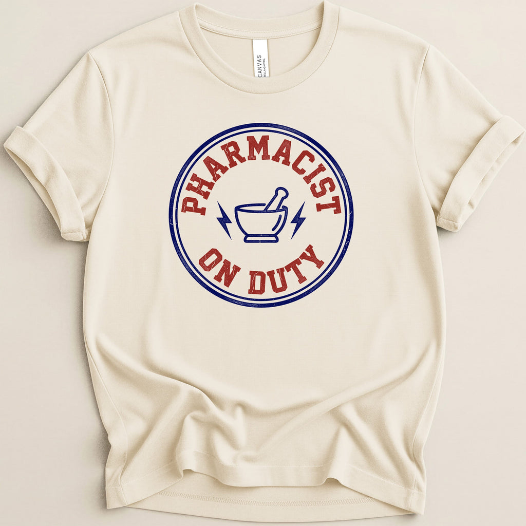 Cream t-shirt with "Pharmacist On Duty" text and lightning bolt symbol.